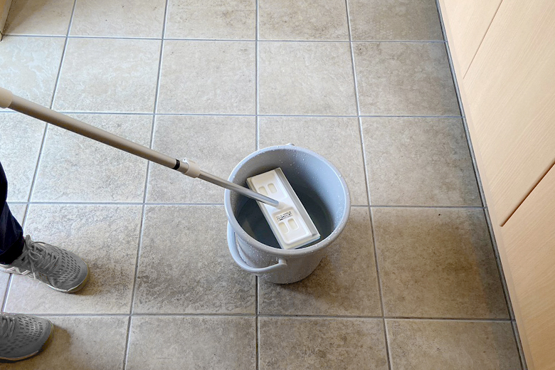 玄関タイルブラシにバケツの水を含ませる